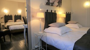 A hotel room with two beds, a small table, and a lamp. - Hotel Ecu de France (Mauriac)