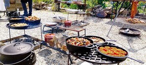An outdoor cooking setup with multiple grills and pots. - Hôtel De France Restaurant Grill - Domfront (Domfront en Poiraie)