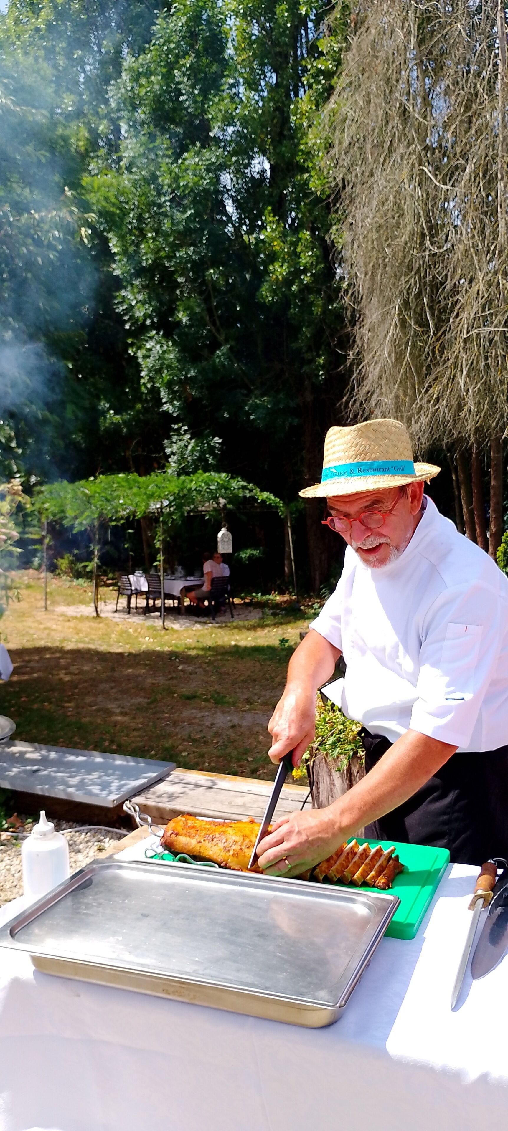 Una persona cortando carne en una parrilla al aire libre.