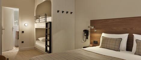 A hotel room with a bunk bed, a wooden headboard, a bedside phone, and a checkered bedspread.