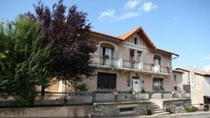 A two-story building with a balcony, a stone base, and a red roof. - Hotel Bayle (Belcaire)