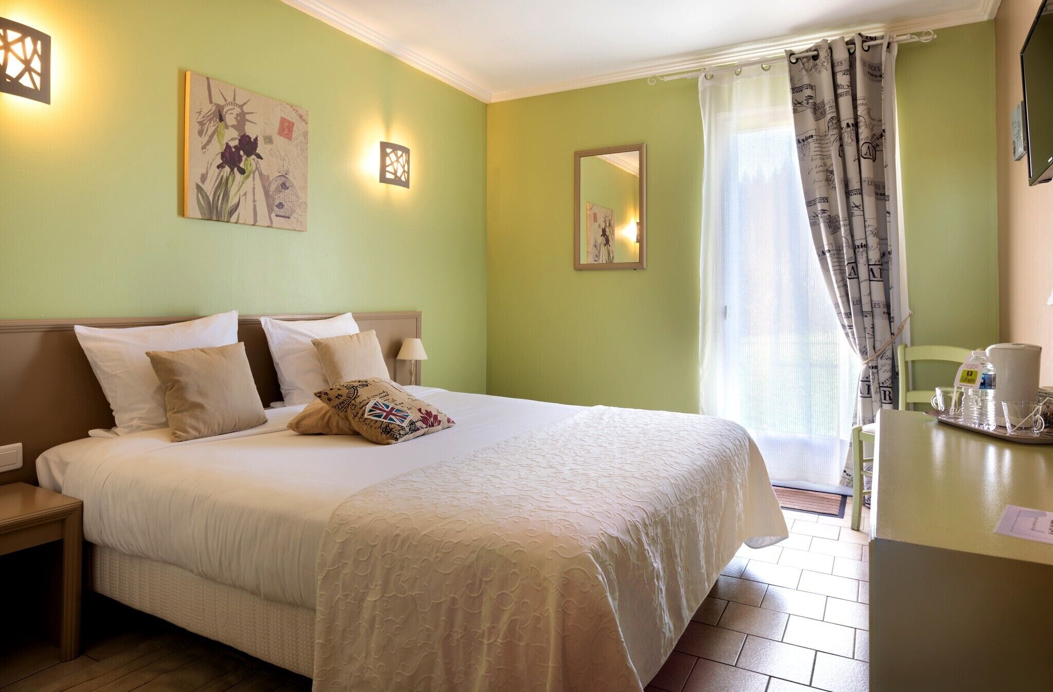 Quarto de hotel bem arrumado, com cama, mesas de cabeceira, escrivaninha e uma cadeira.