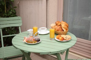 Una mesa verde con alimentos para el desayuno, como croissants, jugo y una taza de café.