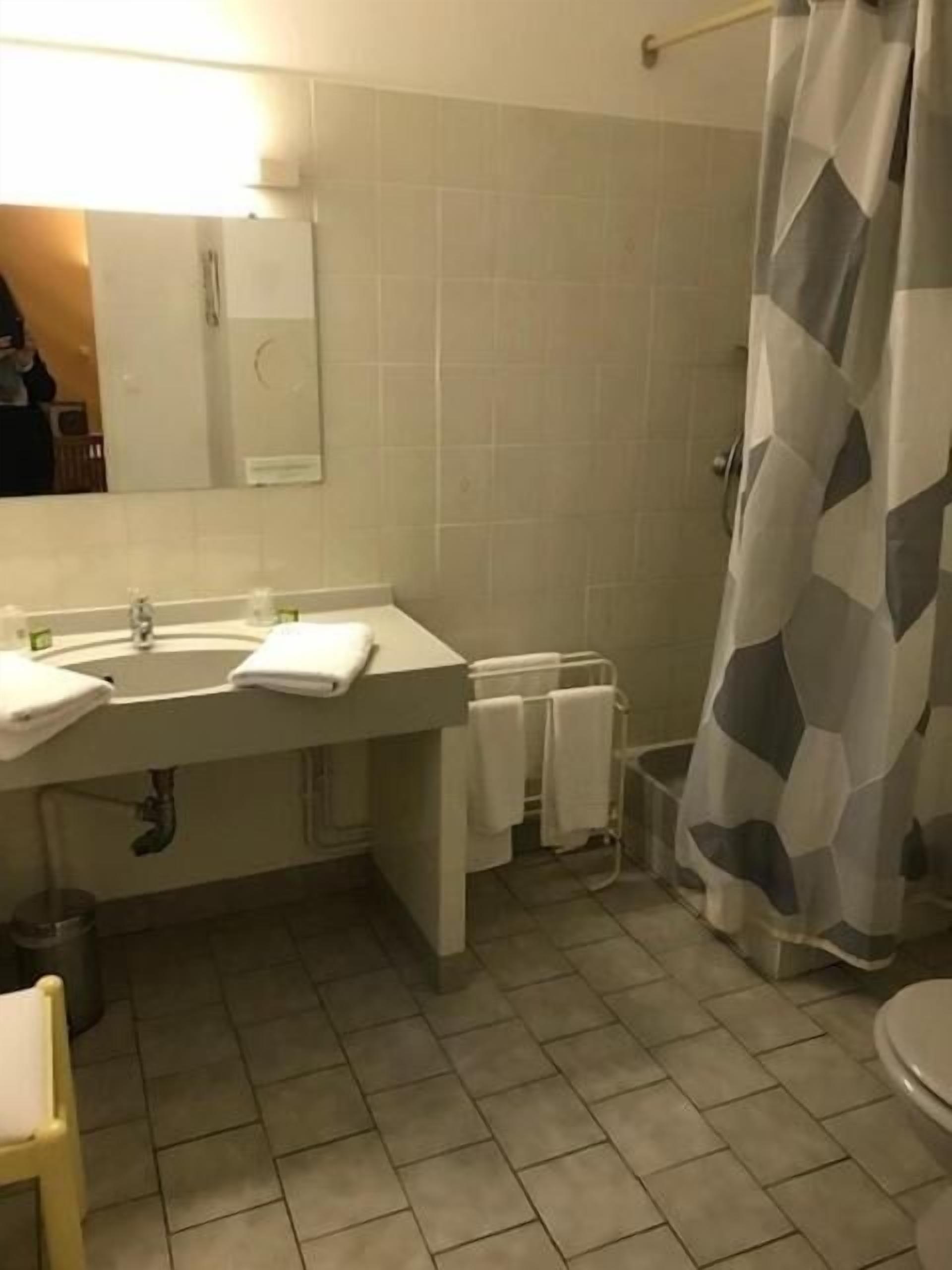 A bathroom with a sink, mirror, and shower curtain.