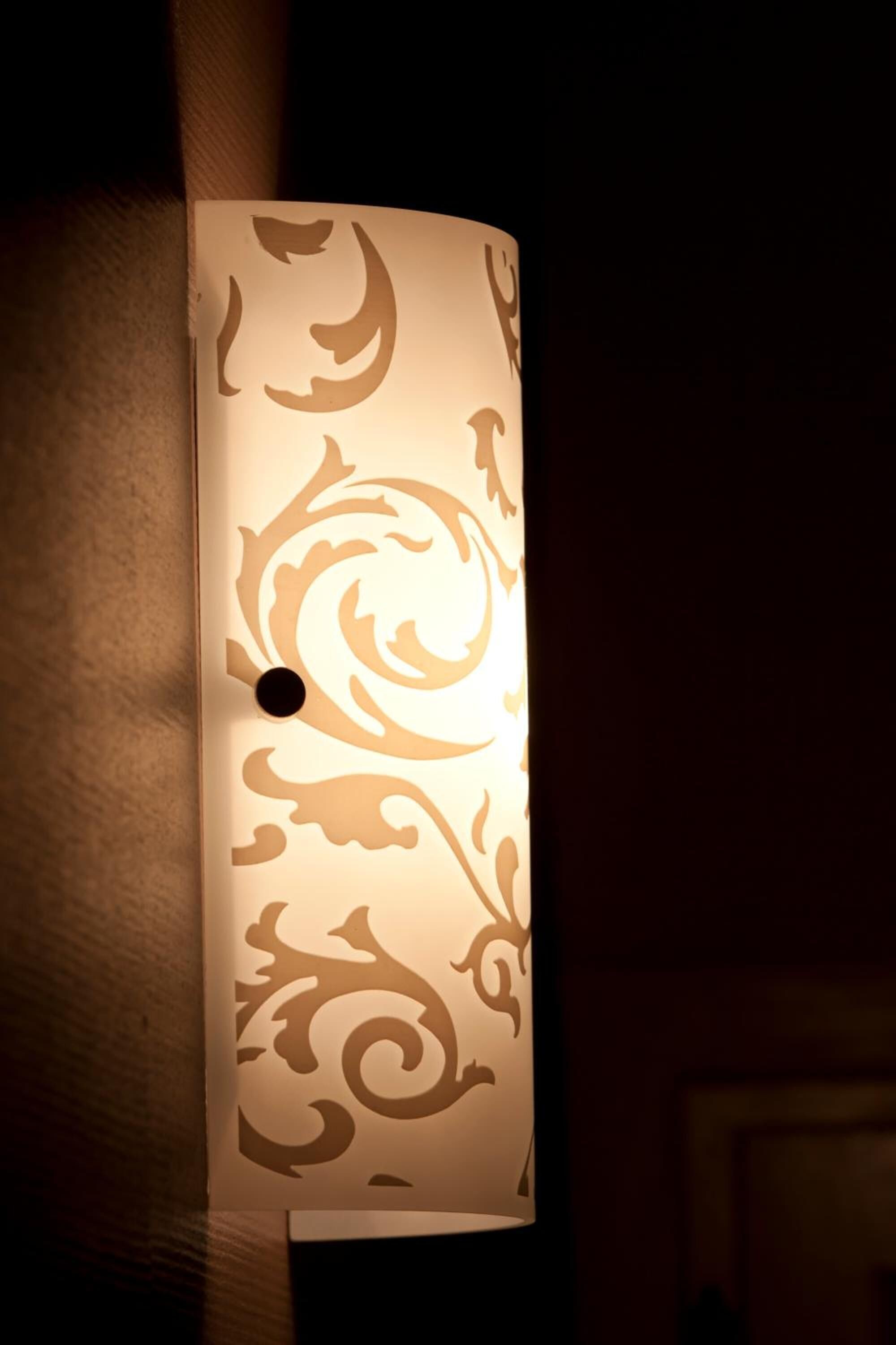 A wall-mounted light fixture with a decorative pattern.