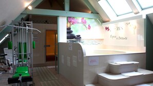 Un área de spa con bañera de hidromasaje, equipo de ejercicio y una escalera que conduce a una habitación privada.