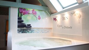 Zona de spa con hidromasaje, pared con el texto 'ZEN' y 'Espaço de Détenção', y un mural de orquídeas púrpuras y rocas.