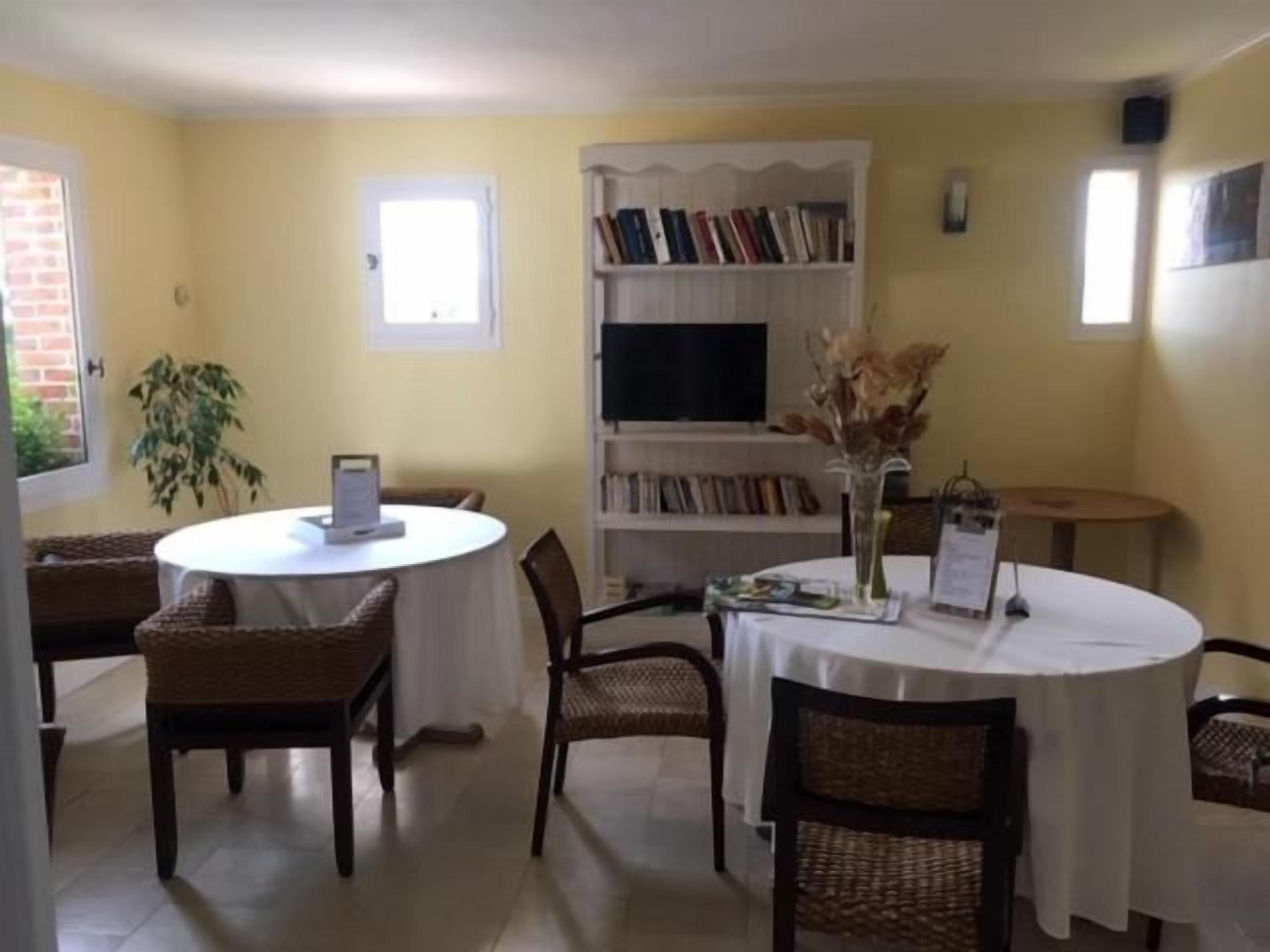 Un comedor con una mesa redonda, sillas, una estantería y una planta.