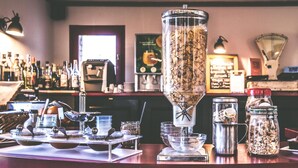 Zona de bar con una máquina de café, un molinillo y varios botes de ingredientes.