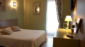 Une chambre d’hôtel avec un lit, une lampe de chevet et une petite table sur laquelle se trouve une télécommande.