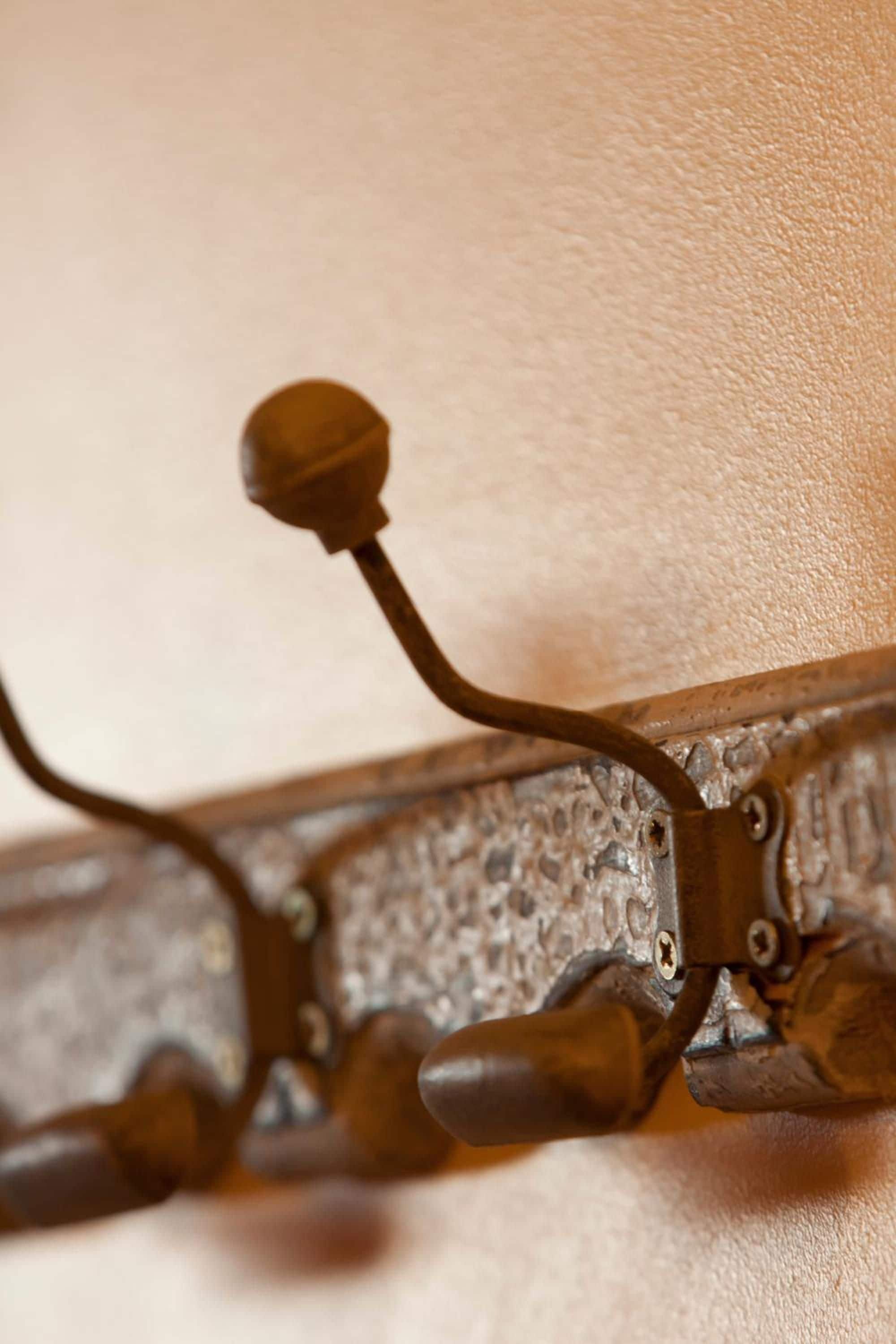 A close-up of a metal wall-mounted coat rack with multiple hooks.
