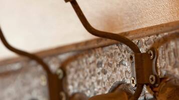 A close-up of a metal wall-mounted coat rack with multiple hooks.