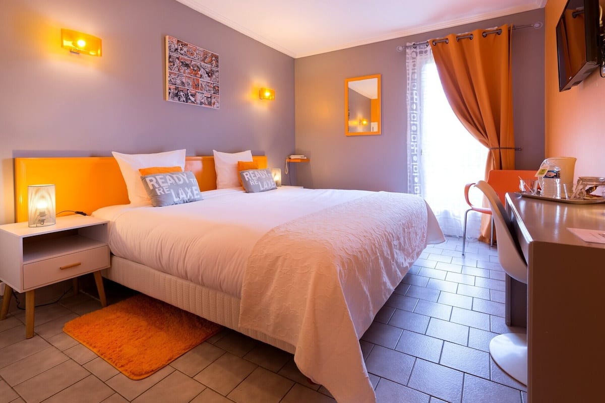 A hotel room with a large bed, bedside tables, a desk, and a chair.