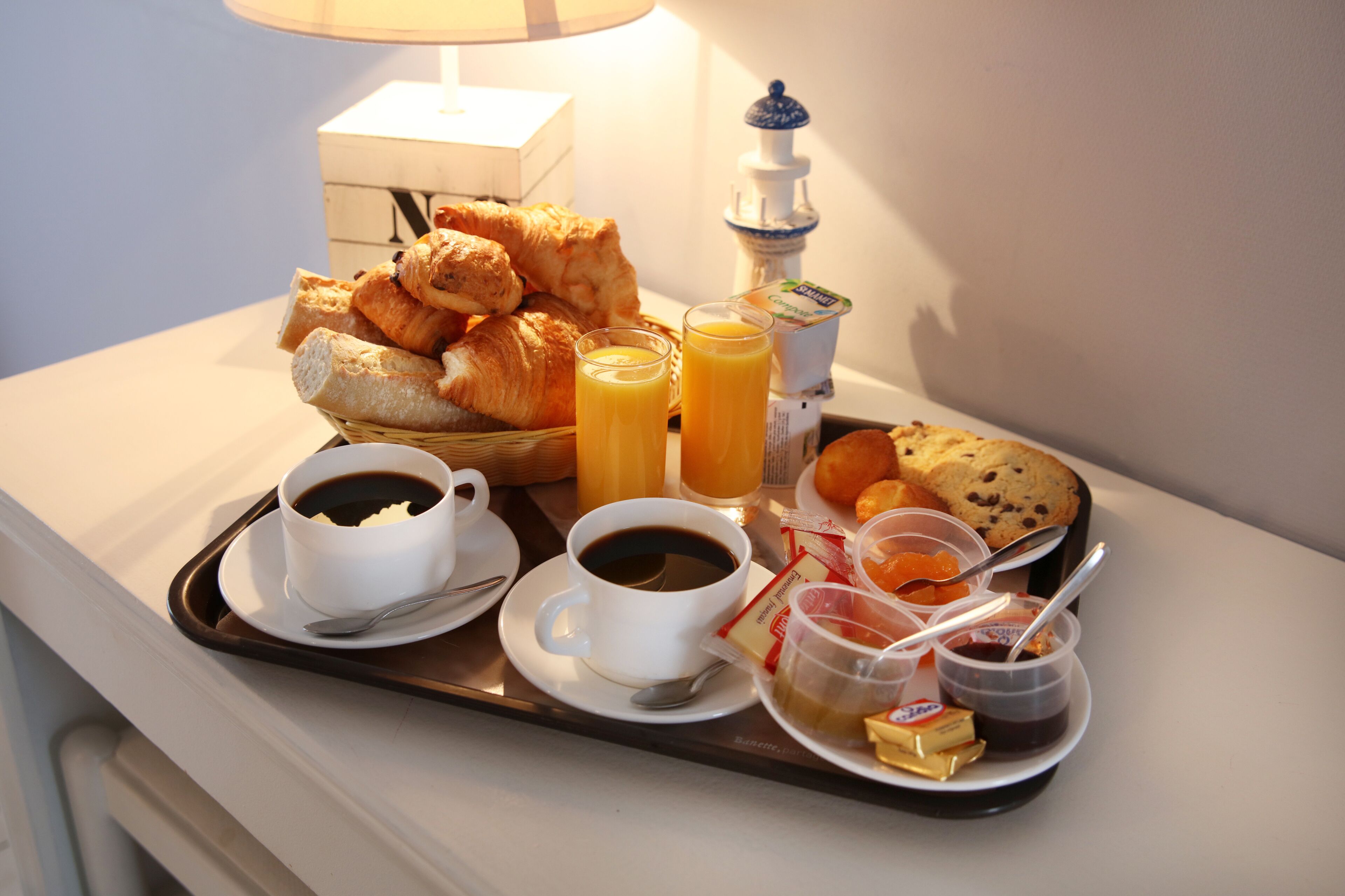 A breakfast tray with croissants, juice, coffee, and butter on a hotel table.