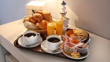 A breakfast tray with croissants, juice, coffee, and butter on a hotel table.