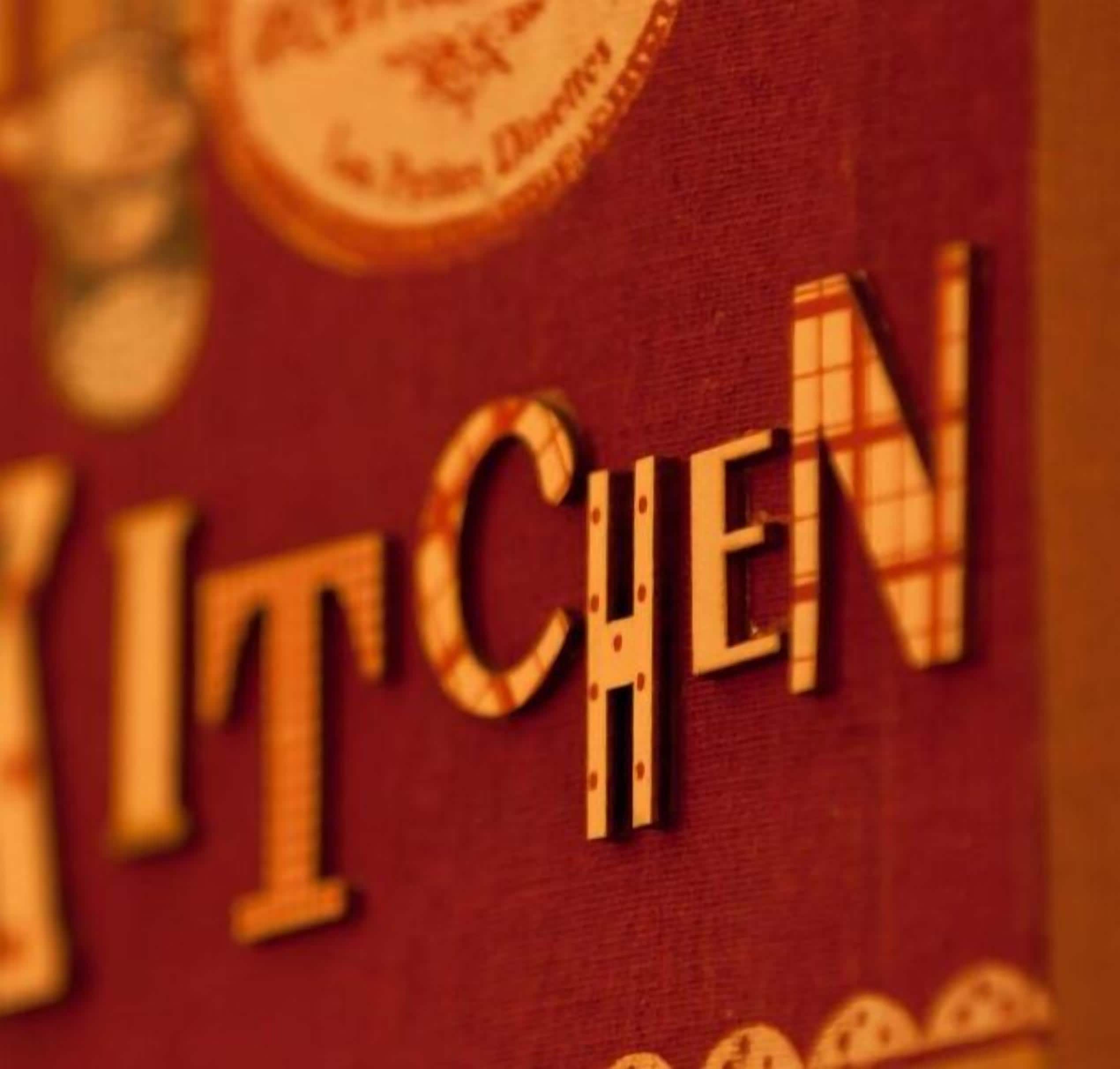 Close-up de uma placa com a palavra 'KITCHEN' em letras grandes e em negrito.