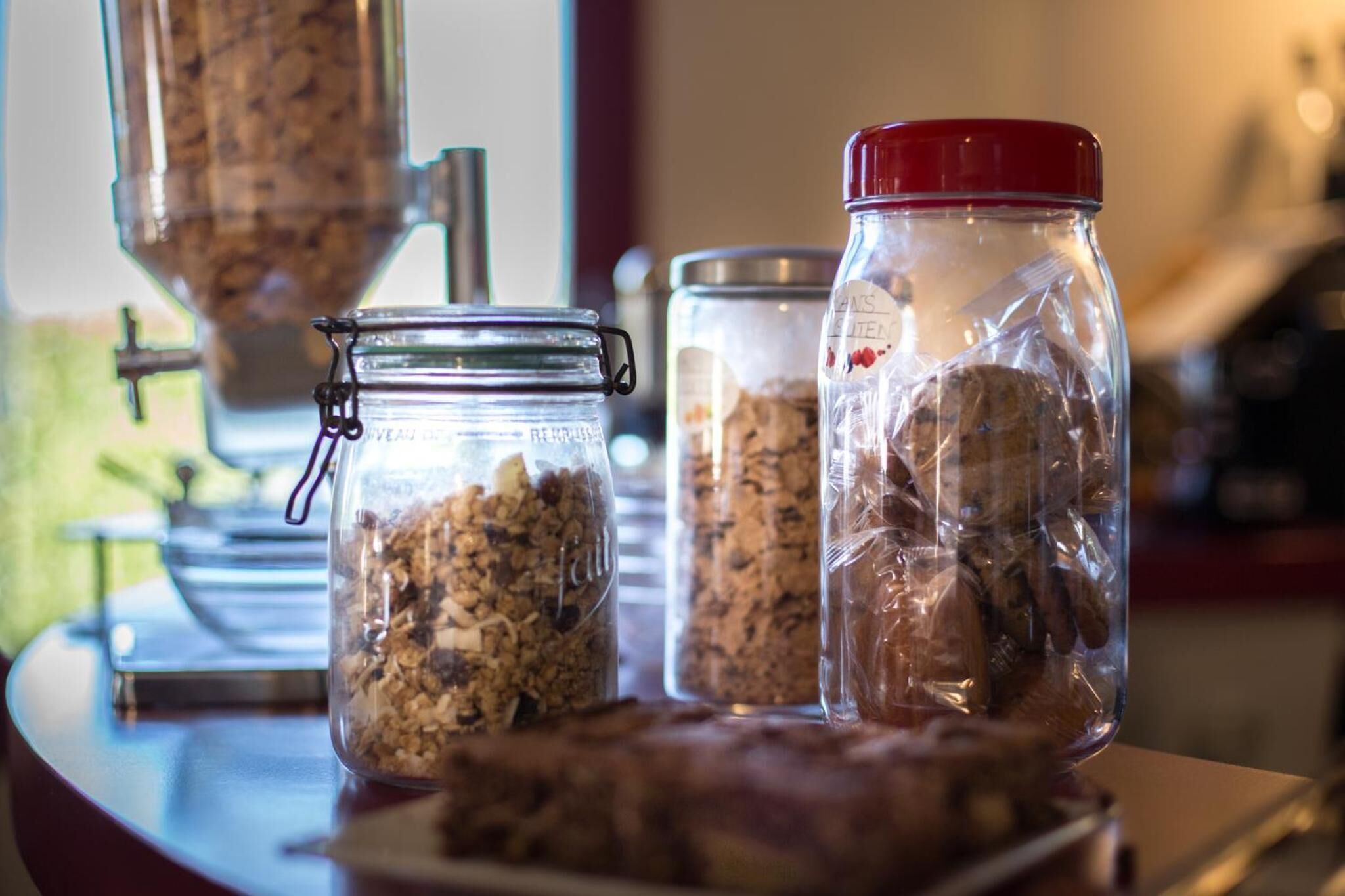 Uma bancada de cozinha com três potes de vidro contendo granola e outros alimentos.