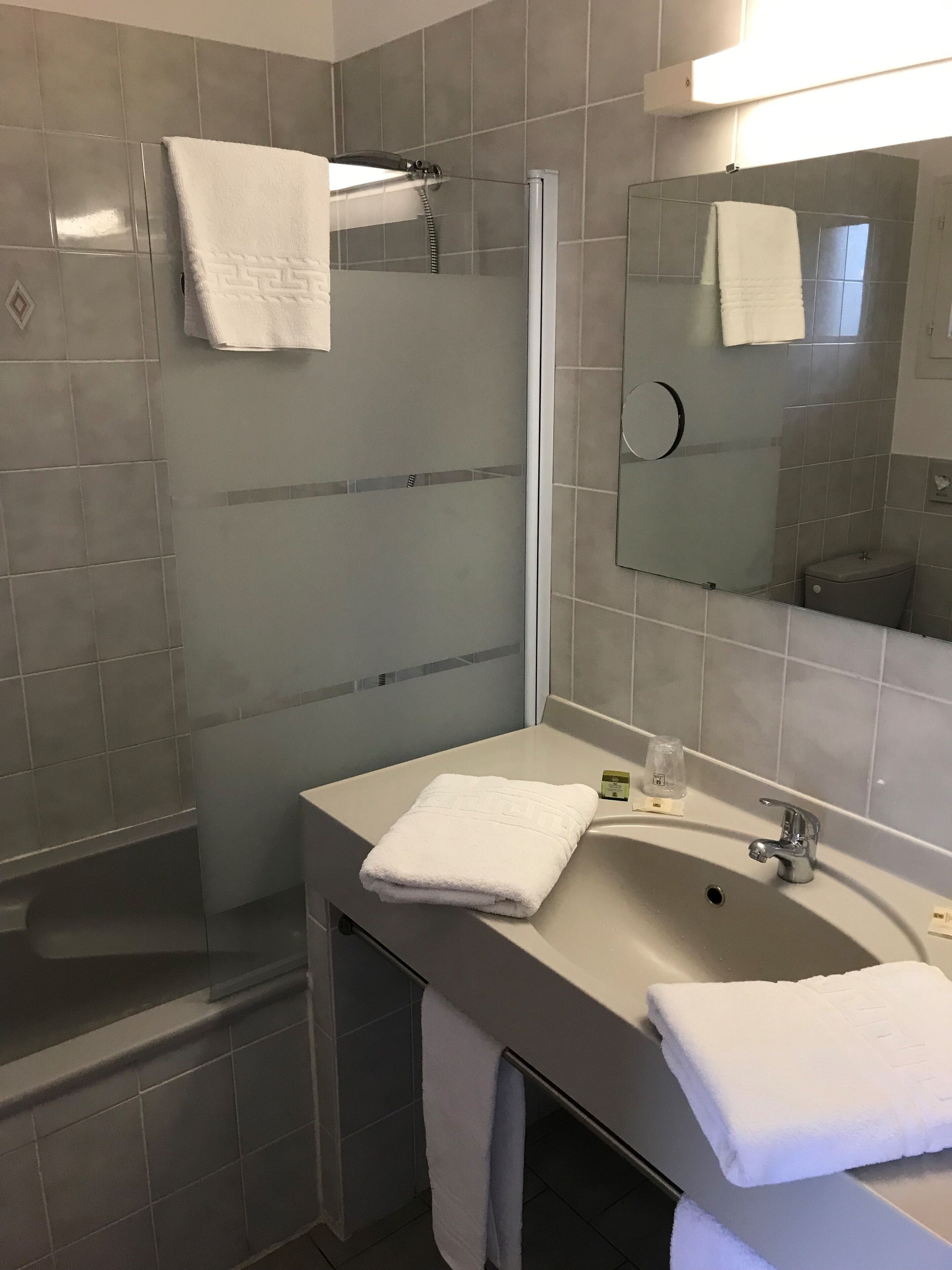 Un bagno moderno con doccia, lavandino e specchio.