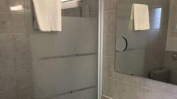 Un bagno moderno con doccia, lavandino e specchio.