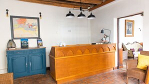 Ein Zimmer mit einem Holzbüro, einer Karte an der Wand, einem blauen Schrank, Korbstühlen und einem Fliesenboden.