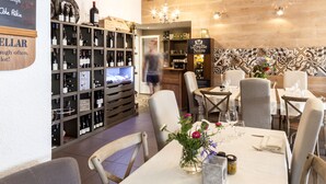 L’intérieur d’un restaurant, avec une cave à vin, des tables, des chaises et un lustre.