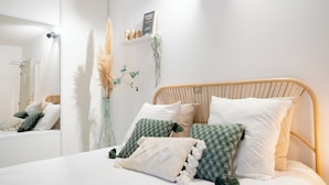 Un lit bien fait, avec une tête de lit en bois, un miroir et des coussins décoratifs.