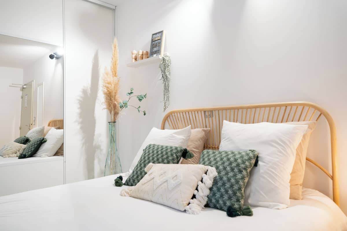A neatly made bed with a wooden headboard, a mirror, and decorative pillows.
