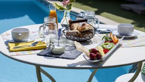 Une table de petit-déjeuner installée avec une piscine en arrière-plan.