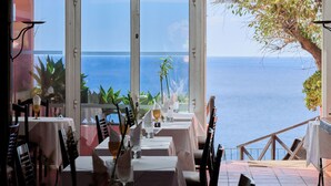Un ristorante con tavoli apparecchiati per la cena, affacciato su una vista panoramica dell'oceano.