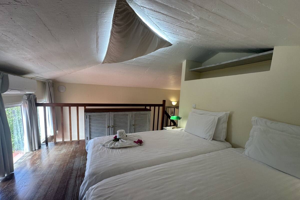 A hotel room with two beds, a balcony, and a view of the outdoors.