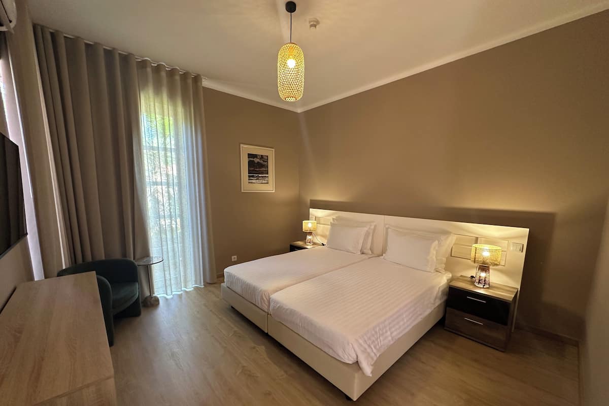 A hotel room with a large bed, bedside tables, a desk, and a chair.