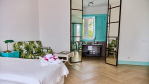 Una camera da letto con un letto, un comodino, uno specchio e vista sul bagno.