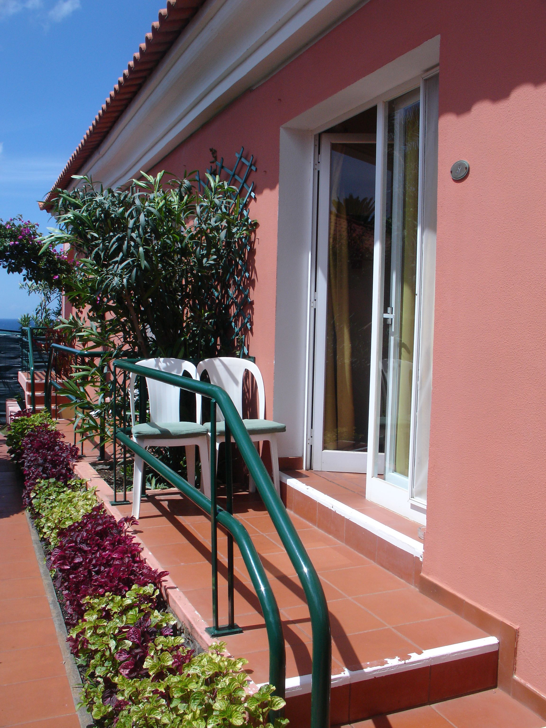 A building with a red exterior, a white door, and a green staircase leading to a balcony.