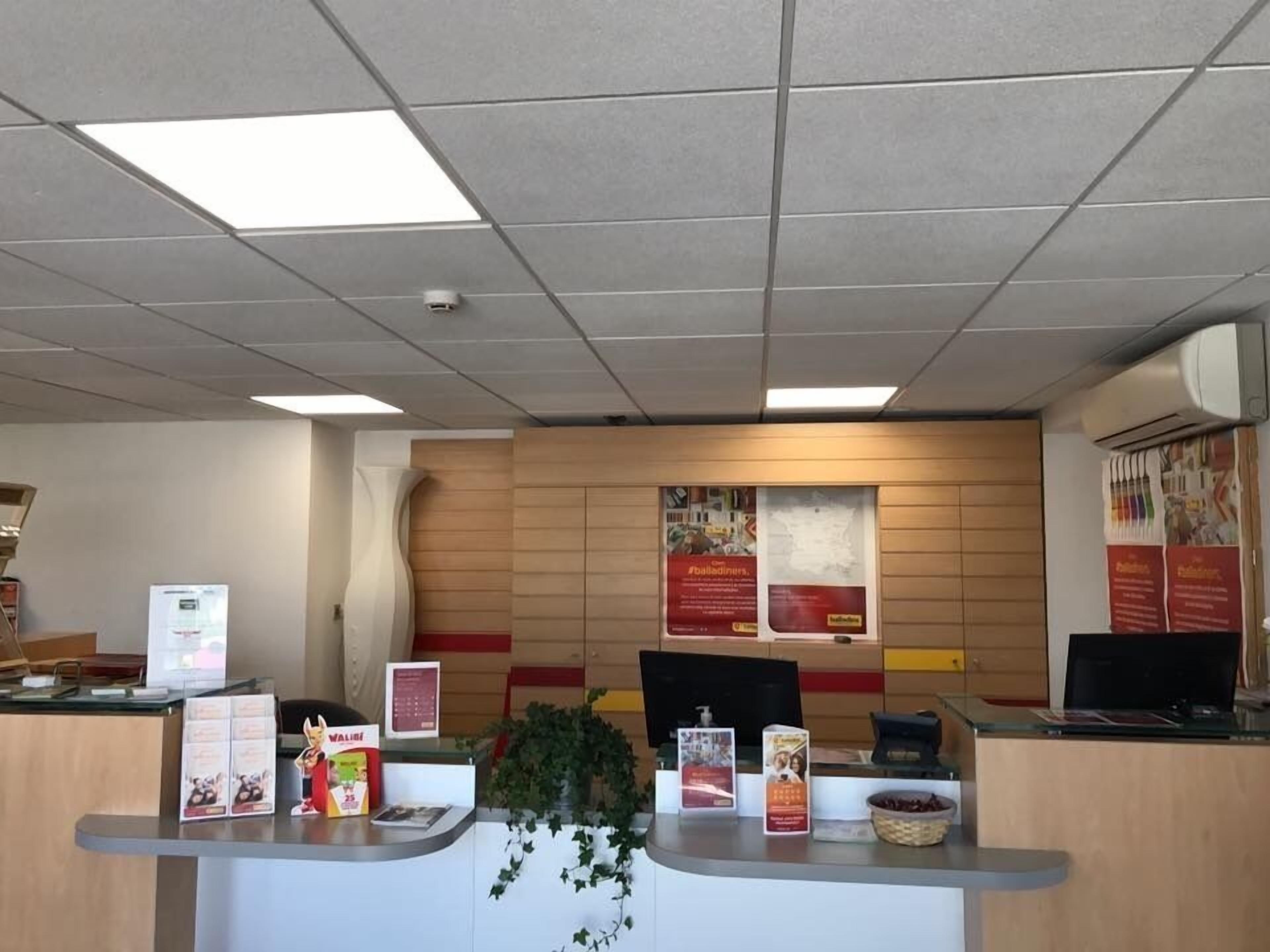A reception desk with informational posters, a plant, and a computer.