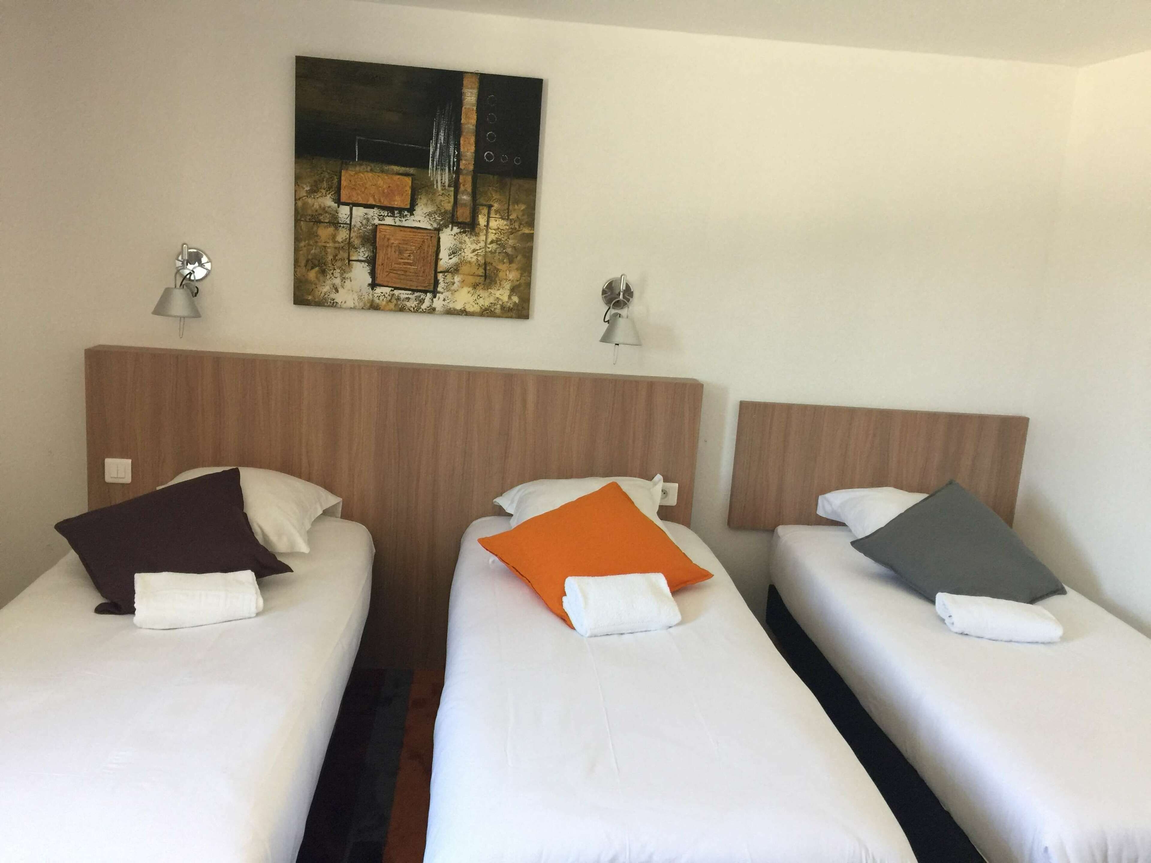 A hotel room with two single beds, each with a pillow and a lamp on the nightstand.