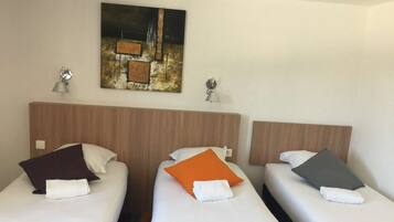 A hotel room with two single beds, each with a pillow and a lamp on the nightstand.