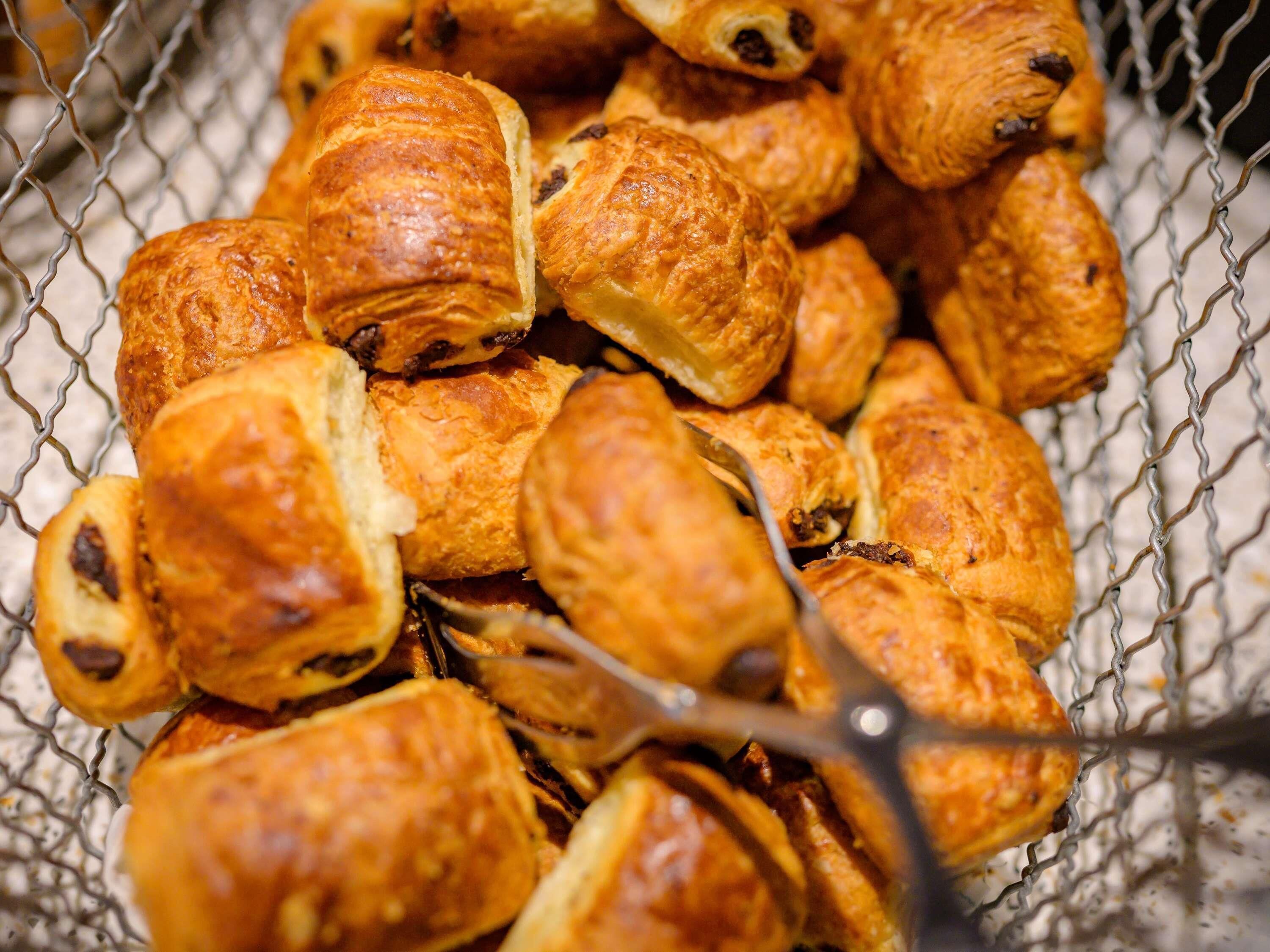 Una cistella plena de pa de mel i probablement croissants, amb una malla metàl·lica.