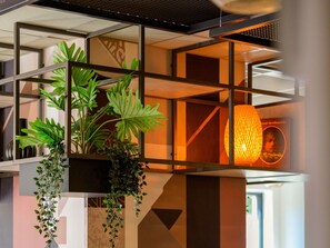 A modern interior with geometric shelving, hanging plants, and a warm ambient light fixture. - ibis Konstanz (Konstanz)