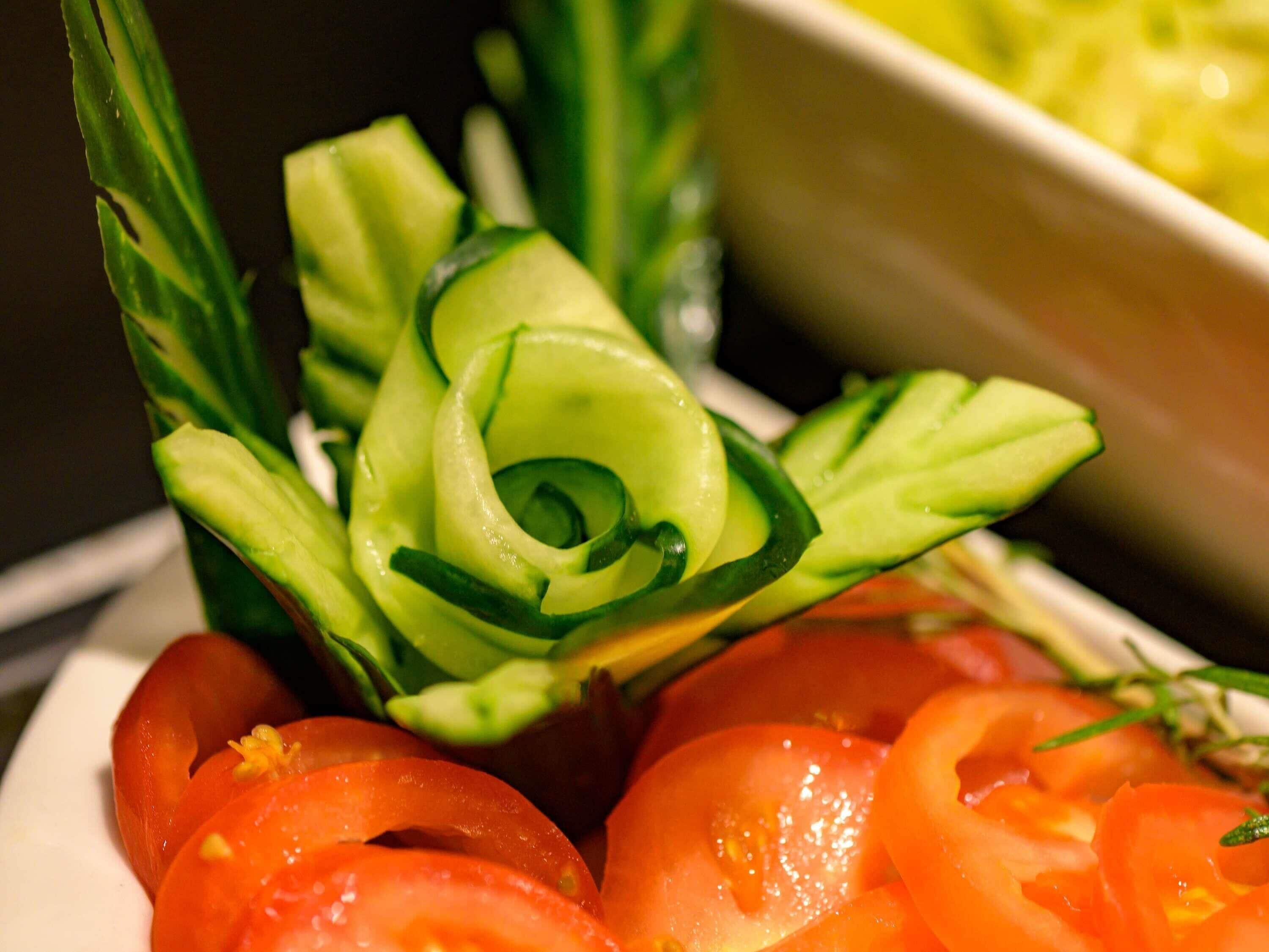 Ein Teller mit geschnittenem Gemüse, darunter eine Gurke im Spiralstil und Tomaten.