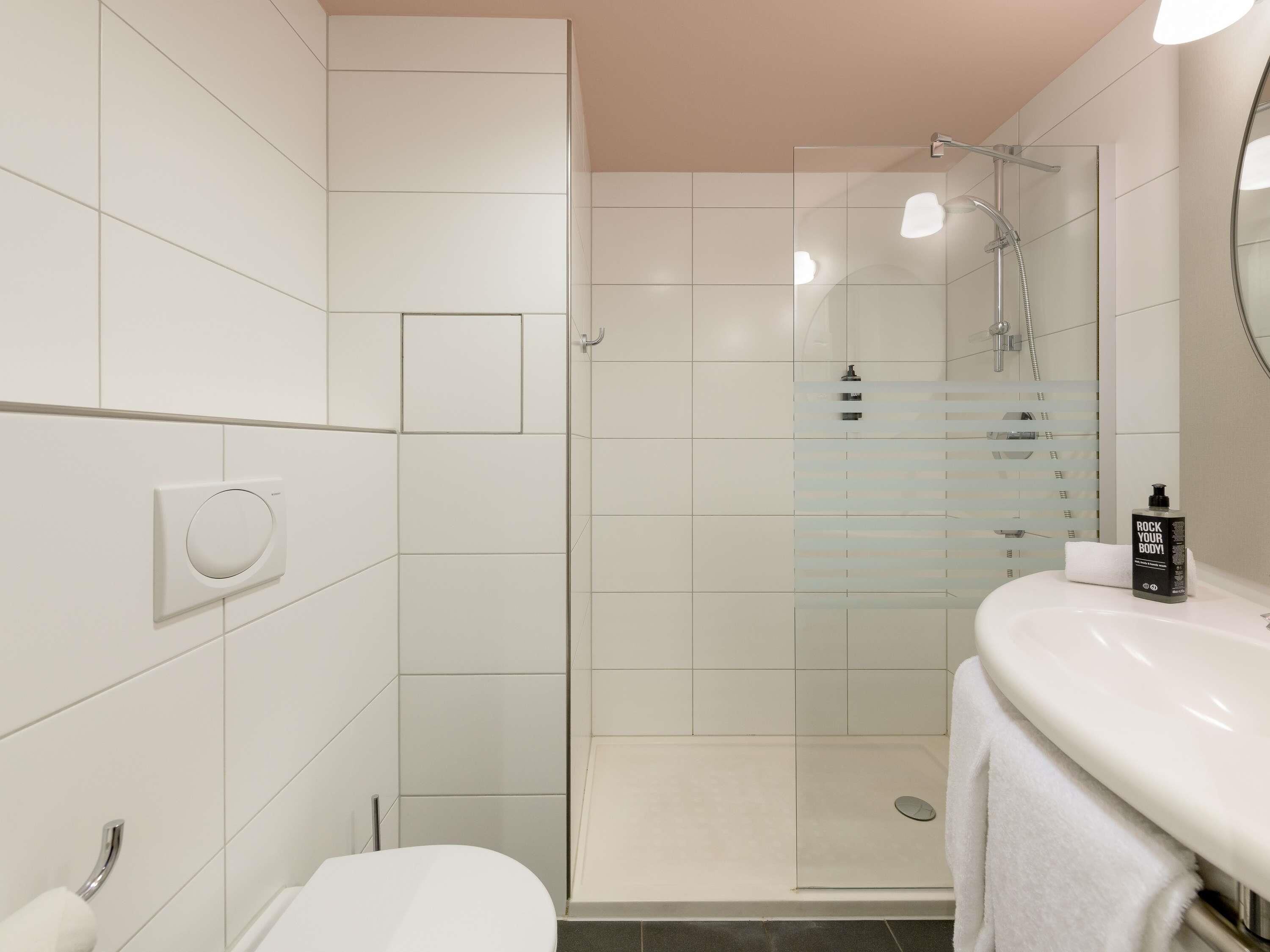 A modern bathroom with a glass-enclosed shower, a white toilet, and a sink with a towel.