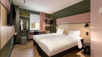 Ein modernes Hotelzimmer mit einem großen Bett, einem Schreibtisch, einem Kleiderschrank und einem Fernseher.