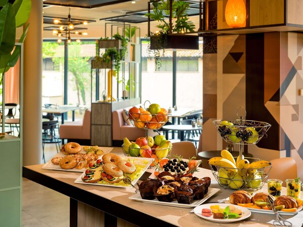 Uma mesa de buffet com diversos itens de comida, incluindo doces, frutas e sobremesas.