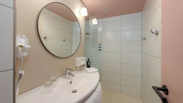 A modern bathroom with a round mirror, a sink, and a glass shower enclosure.