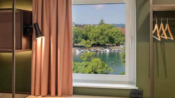 Ein Zimmer mit Blick auf ein Gewässer, einem Schreibtisch und einem Hängesessel.