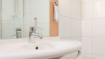 Une salle de bain avec un lavabo blanc, un robinet chromé et une serviette suspendue à un porte-serviettes.