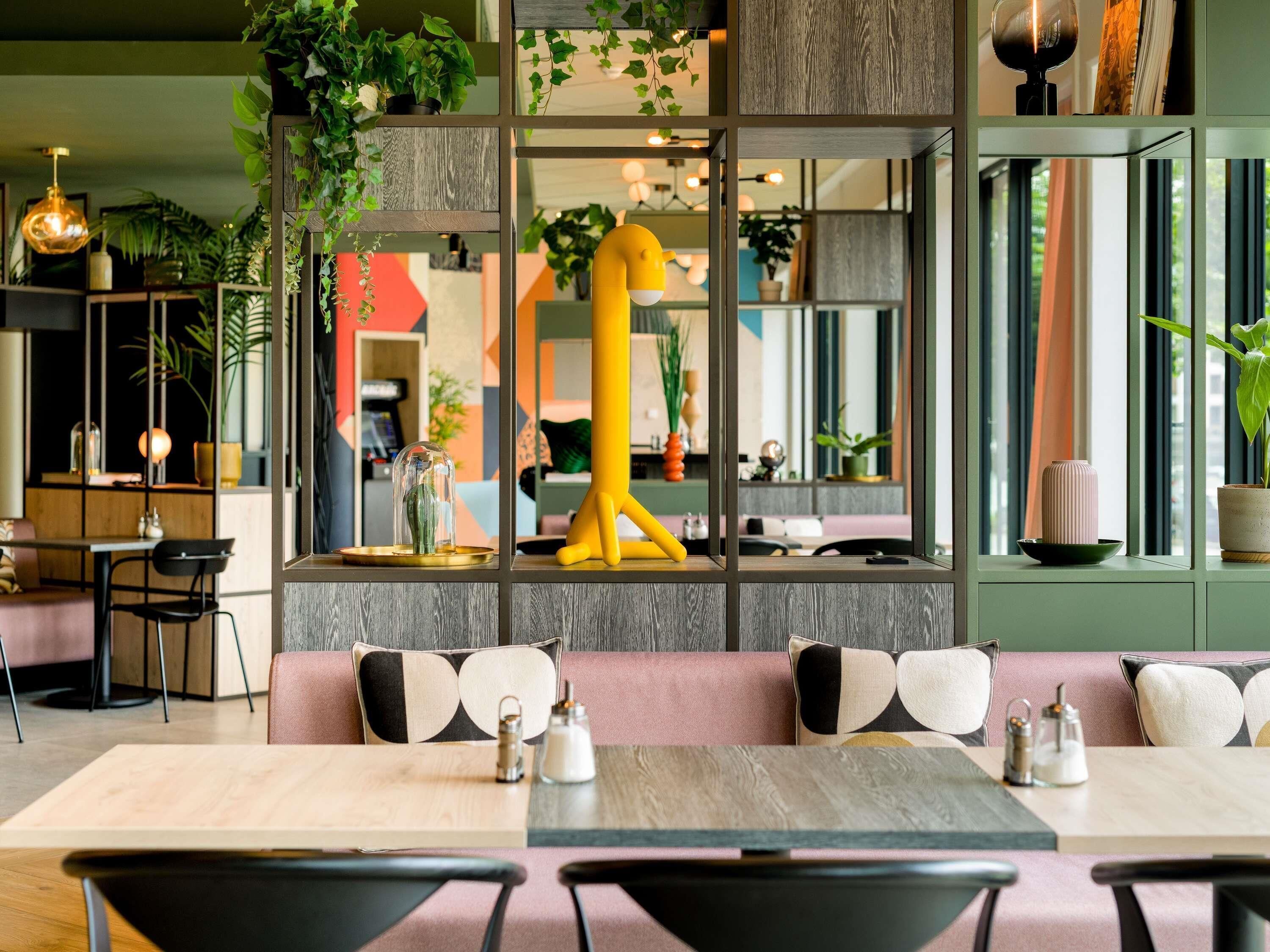 Ein modernes Interieur mit einer Sitzecke, einer großen, gelben Skulptur und verschiedenen Pflanzen.