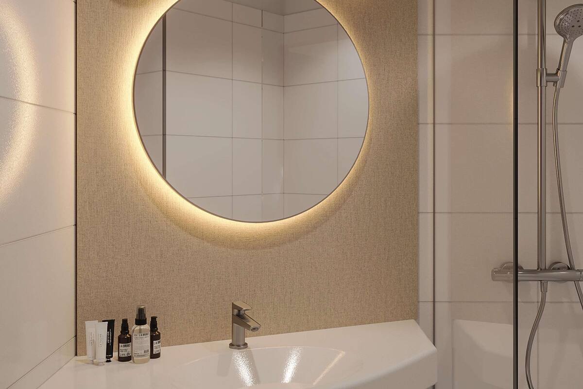 Un baño con un espejo redondo, un lavabo y una ducha.