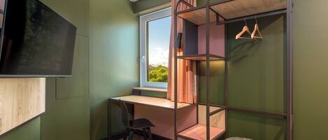 A compact room with a bunk bed, a desk, a chair, and a television.