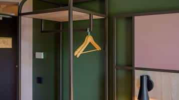 Una habitación con un perchero de madera colgante, una lámpara de pared negra y una pared verde.