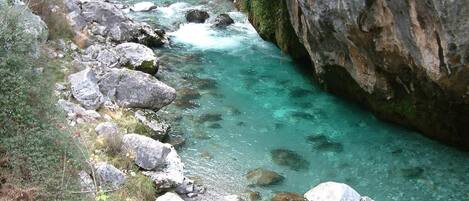 Un río que serpentea por un desfiladero rocoso con aguas cristalinas y grandes rocas.